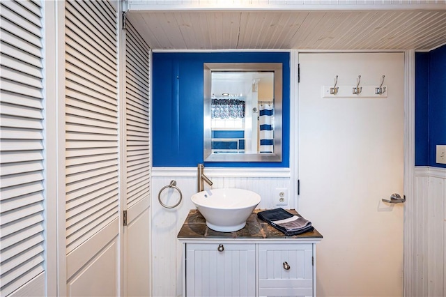 bathroom featuring a wainscoted wall, wooden ceiling, and vanity