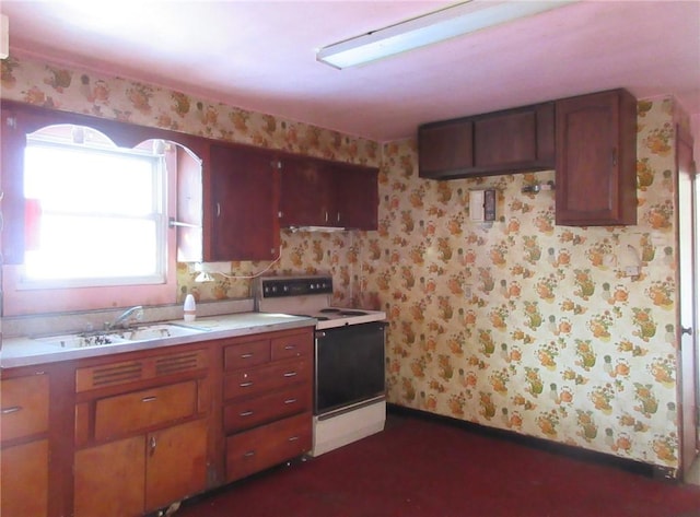 kitchen featuring a sink, electric range, light countertops, and wallpapered walls