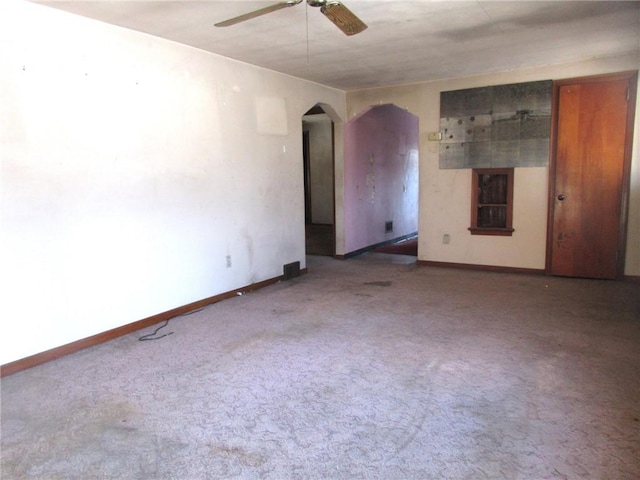 spare room with arched walkways, baseboards, carpet, and a ceiling fan