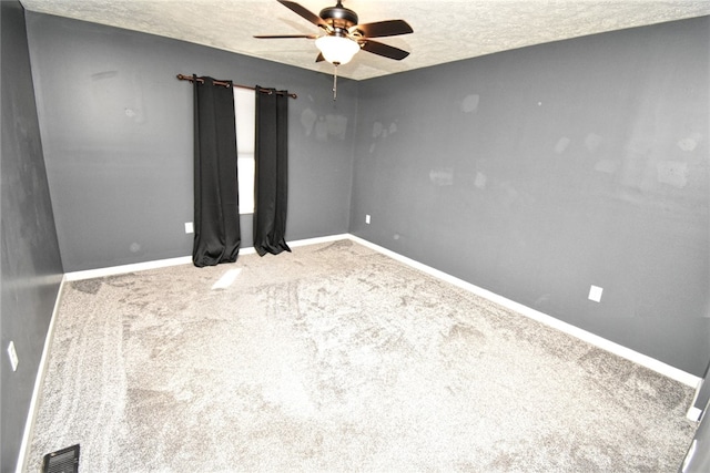 carpeted spare room with baseboards, a ceiling fan, visible vents, and a textured ceiling