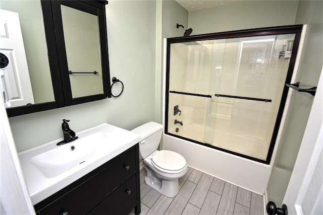 bathroom with vanity, enclosed tub / shower combo, wood tiled floor, a textured ceiling, and toilet