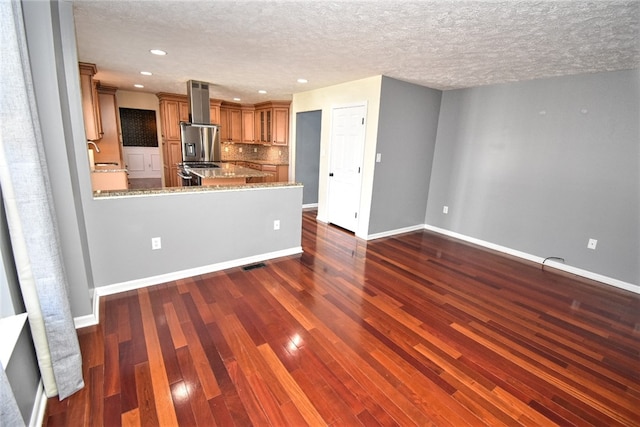 kitchen featuring decorative backsplash, brown cabinets, dark wood-type flooring, and baseboards