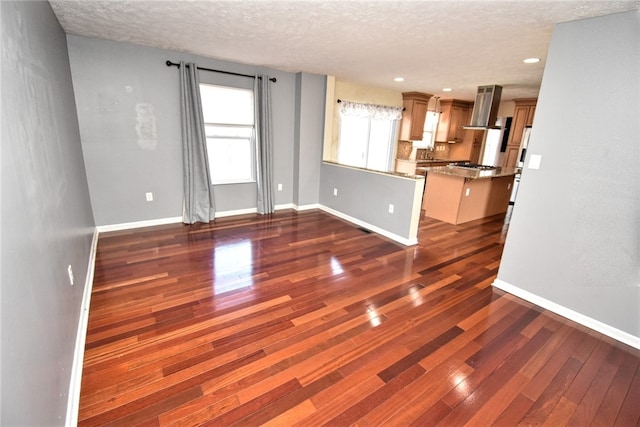 unfurnished living room featuring recessed lighting, baseboards, a textured ceiling, and dark wood finished floors