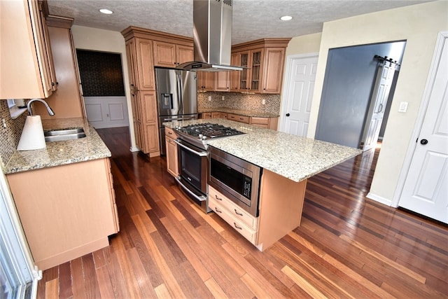 kitchen with a sink, light stone counters, range hood, stainless steel appliances, and dark wood-style flooring