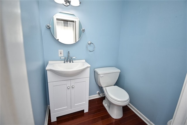 bathroom with toilet, vanity, baseboards, and wood finished floors