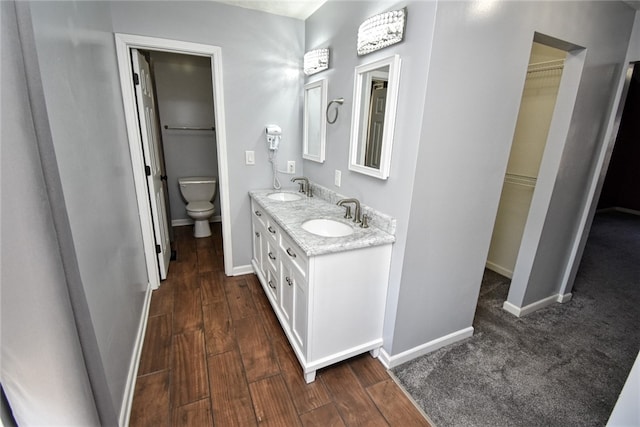 full bath featuring a walk in closet, toilet, wood finished floors, and a sink