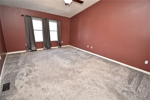 empty room with baseboards, lofted ceiling, carpet floors, a textured ceiling, and a ceiling fan