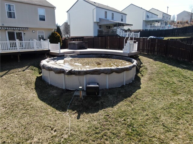 view of swimming pool featuring a fenced backyard, a lawn, a wooden deck, and a hot tub