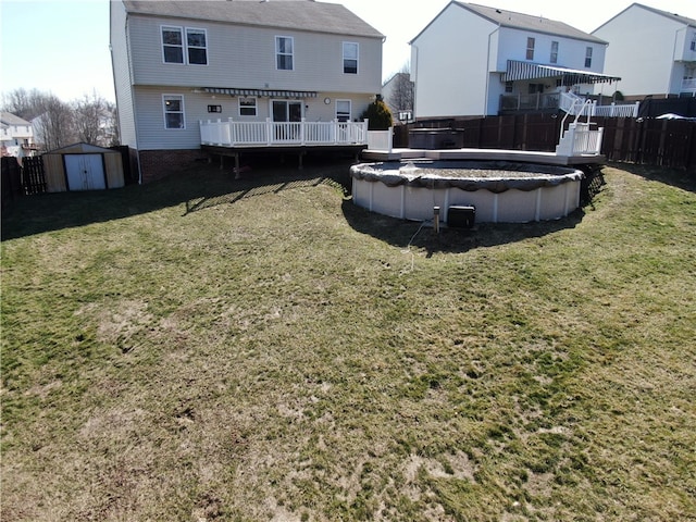 rear view of house featuring a fenced in pool, a shed, a yard, a fenced backyard, and an outdoor structure