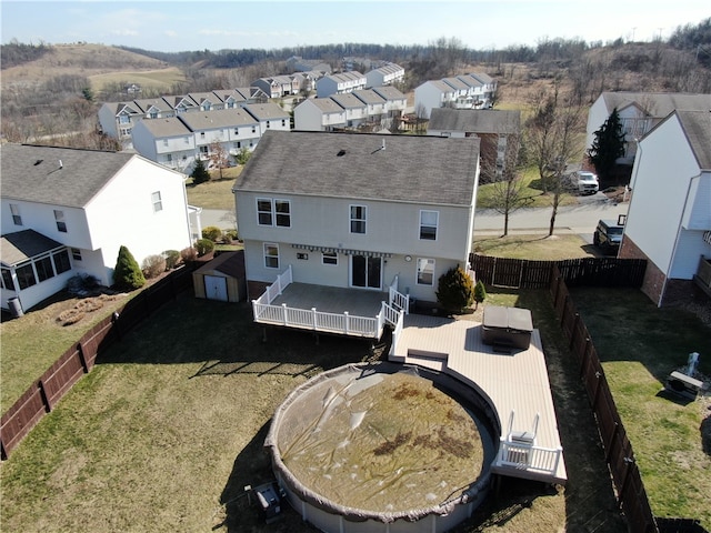 rear view of house with a deck, a fenced backyard, a shed, a residential view, and an outdoor structure