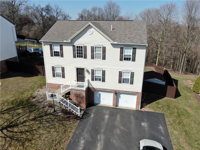 view of front of property with a front lawn, aphalt driveway, an attached garage, a shingled roof, and brick siding