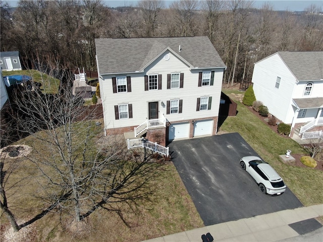 view of front facade with an attached garage, driveway, and a shingled roof