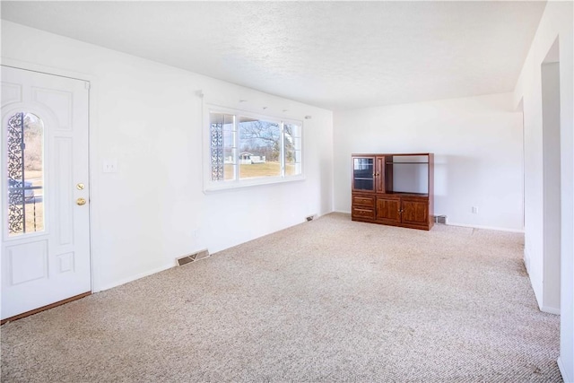 unfurnished living room with visible vents, carpet flooring, and a textured ceiling