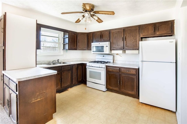 kitchen with white appliances, dark brown cabinets, light floors, and a sink