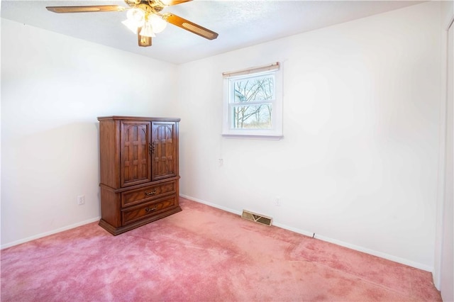 spare room with light carpet, visible vents, a ceiling fan, and baseboards