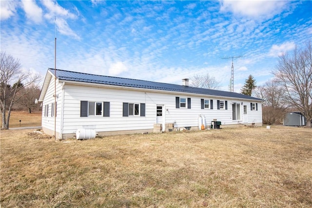 rear view of property featuring metal roof and a yard