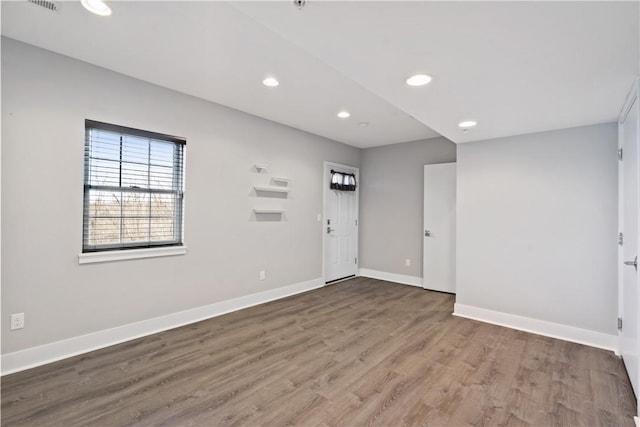 empty room with recessed lighting, wood finished floors, and baseboards