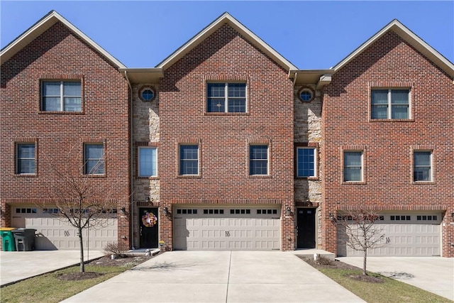 townhome / multi-family property featuring concrete driveway, an attached garage, brick siding, and stone siding