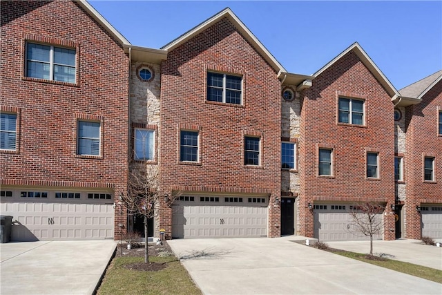 townhome / multi-family property with brick siding, driveway, and a garage