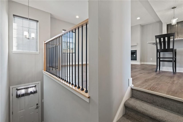 staircase featuring a glass covered fireplace, baseboards, a healthy amount of sunlight, and wood finished floors