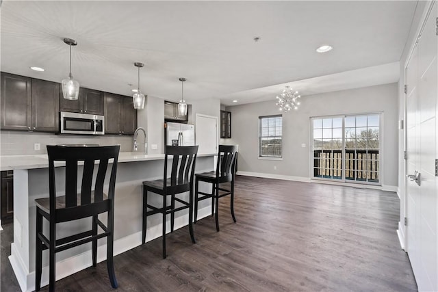 kitchen with dark brown cabinetry, light countertops, decorative backsplash, appliances with stainless steel finishes, and dark wood-style flooring