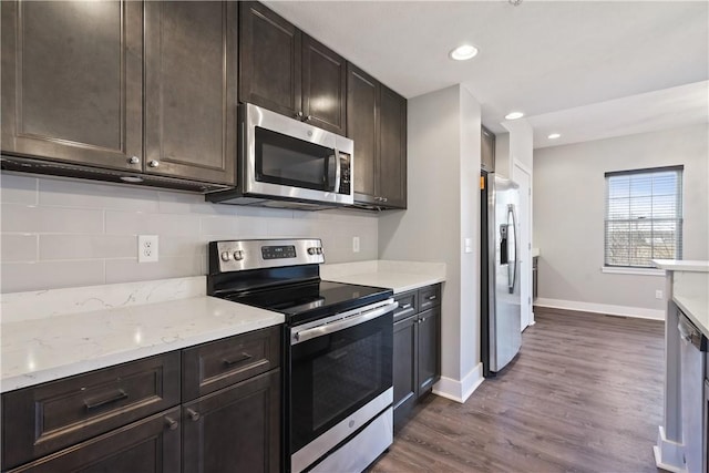 kitchen featuring stainless steel appliances, decorative backsplash, baseboards, dark brown cabinets, and dark wood-style flooring