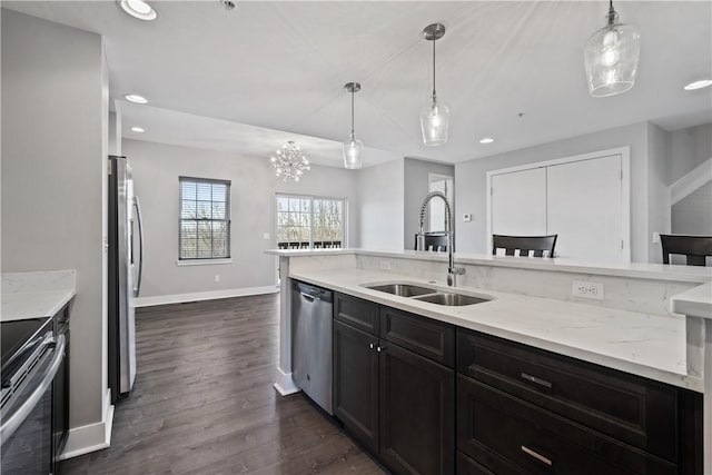 kitchen with a sink, light stone counters, appliances with stainless steel finishes, and recessed lighting