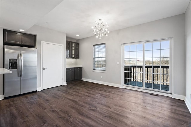 unfurnished dining area with a chandelier, visible vents, dark wood-type flooring, and baseboards