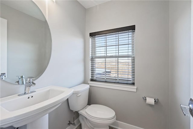 bathroom with toilet, baseboards, and a sink