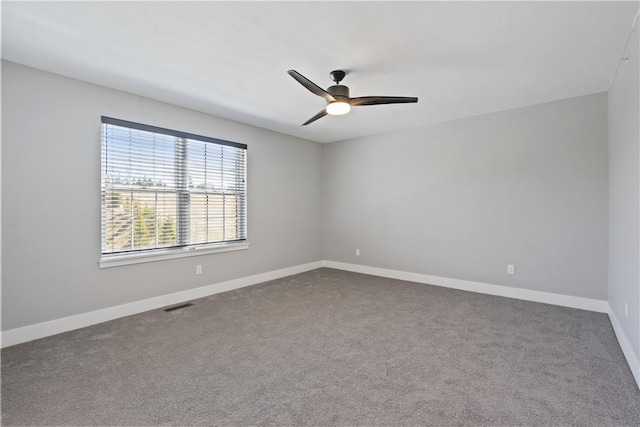 carpeted empty room featuring baseboards, visible vents, and ceiling fan