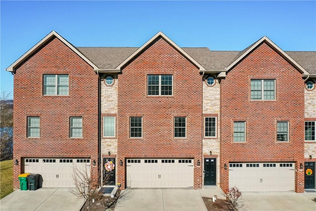 multi unit property with stone siding, an attached garage, and driveway