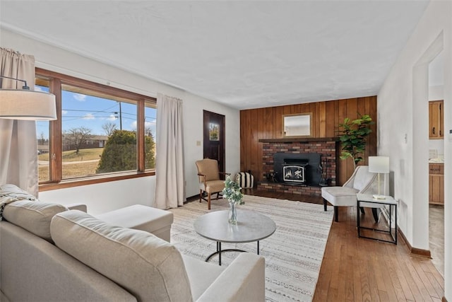 living area featuring light wood finished floors, wooden walls, and baseboards