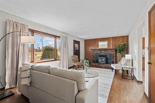 living room featuring wooden walls, baseboards, and wood-type flooring