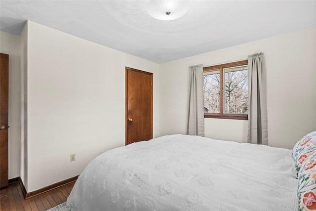 bedroom with dark wood-type flooring and baseboards