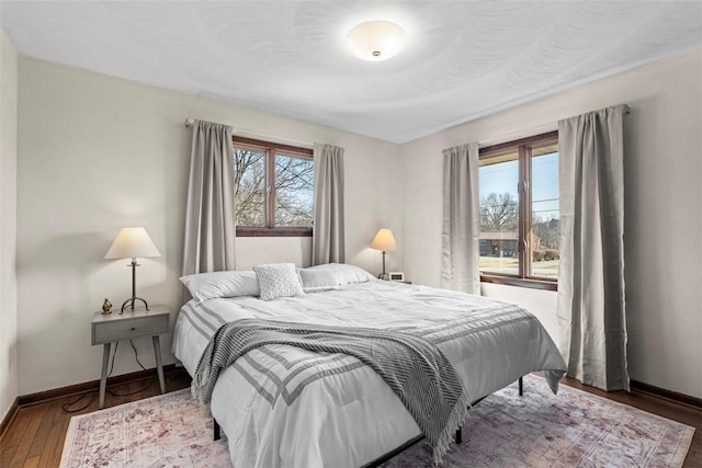 bedroom featuring baseboards, multiple windows, and wood-type flooring