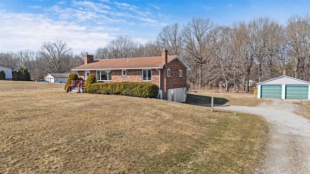 view of front of house featuring an outbuilding, a chimney, brick siding, and a front lawn