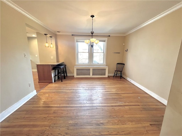 unfurnished dining area featuring hardwood / wood-style floors, baseboards, ornamental molding, and radiator heating unit