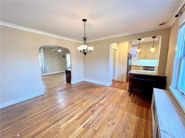 unfurnished dining area featuring light wood-type flooring, visible vents, arched walkways, crown molding, and baseboards