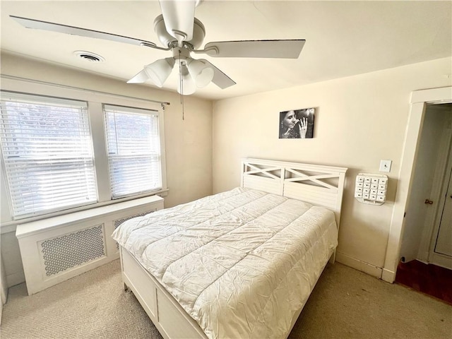 carpeted bedroom featuring visible vents, radiator heating unit, and a ceiling fan