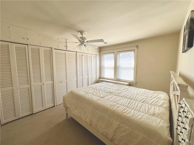 carpeted bedroom with two closets and ceiling fan