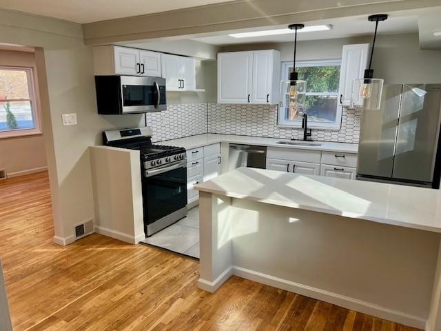 kitchen featuring a sink, light wood finished floors, appliances with stainless steel finishes, and light countertops