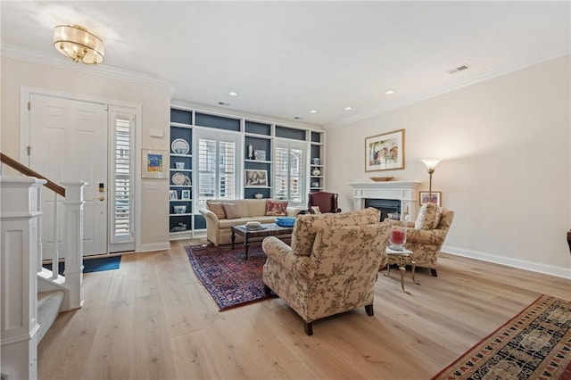 living area featuring light wood finished floors, stairway, a fireplace, and crown molding