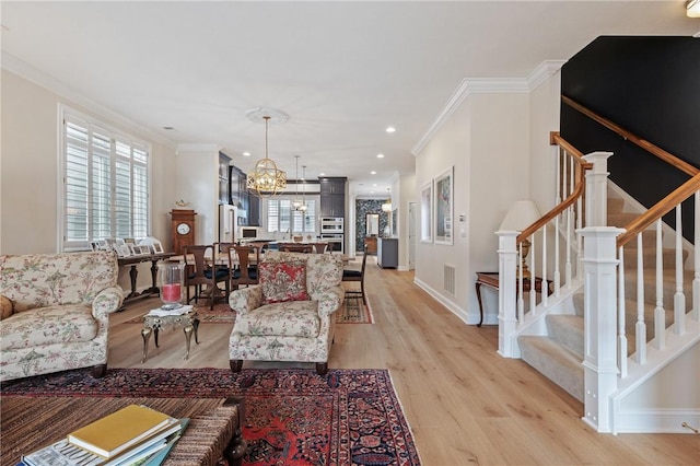 living area featuring light wood-type flooring, a notable chandelier, ornamental molding, and stairs