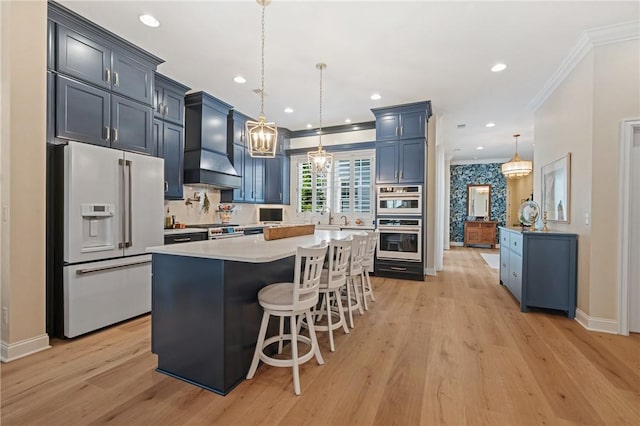 kitchen featuring high end white fridge, crown molding, premium range hood, double wall oven, and a breakfast bar