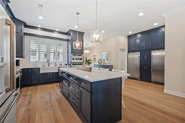 kitchen featuring a breakfast bar, a sink, a kitchen island, appliances with stainless steel finishes, and light countertops