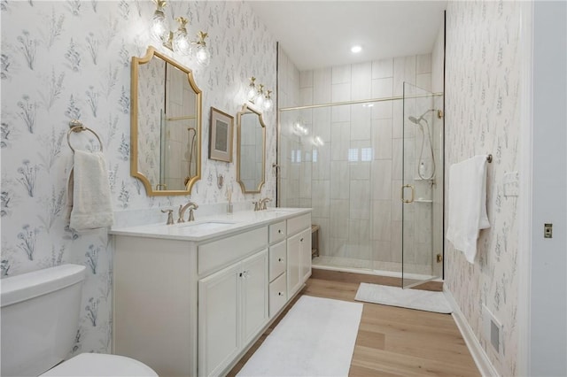 bathroom featuring toilet, wallpapered walls, a shower stall, and a sink