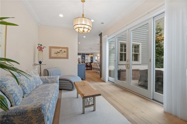 living area with recessed lighting, a notable chandelier, light wood-style flooring, and crown molding