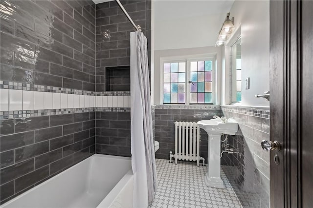 full bath featuring radiator heating unit, shower / bath combo, tile patterned flooring, wainscoting, and tile walls