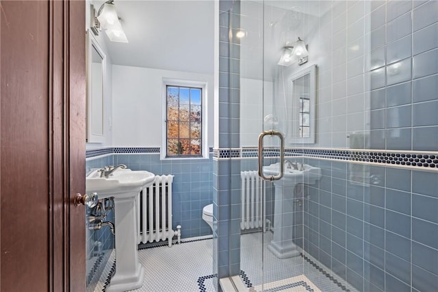 bathroom with tile patterned flooring, a shower stall, toilet, radiator heating unit, and tile walls