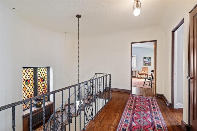 corridor featuring wood finished floors, an upstairs landing, and baseboards